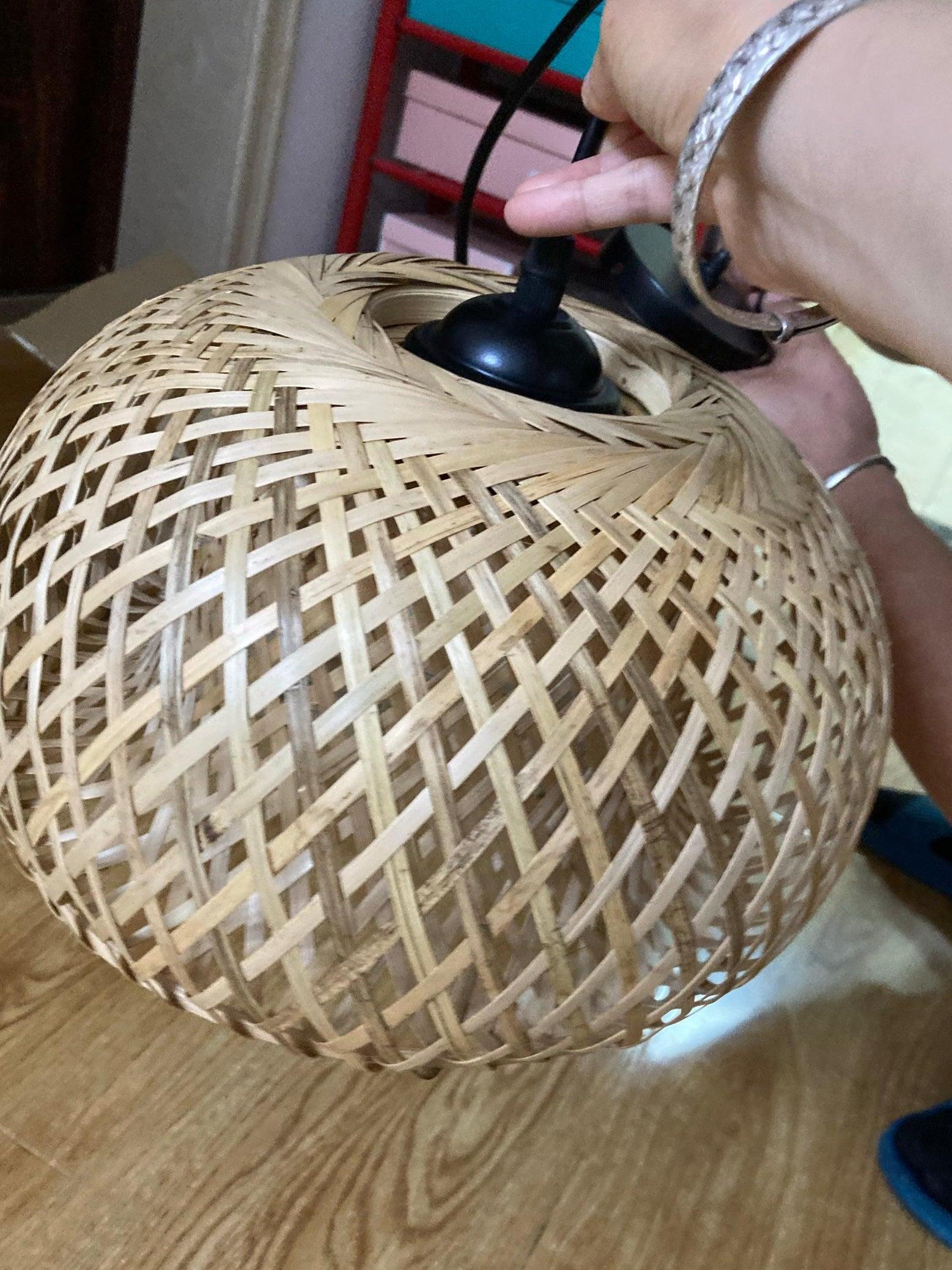 Hand holding top fitting of unlit woven bamboo shade