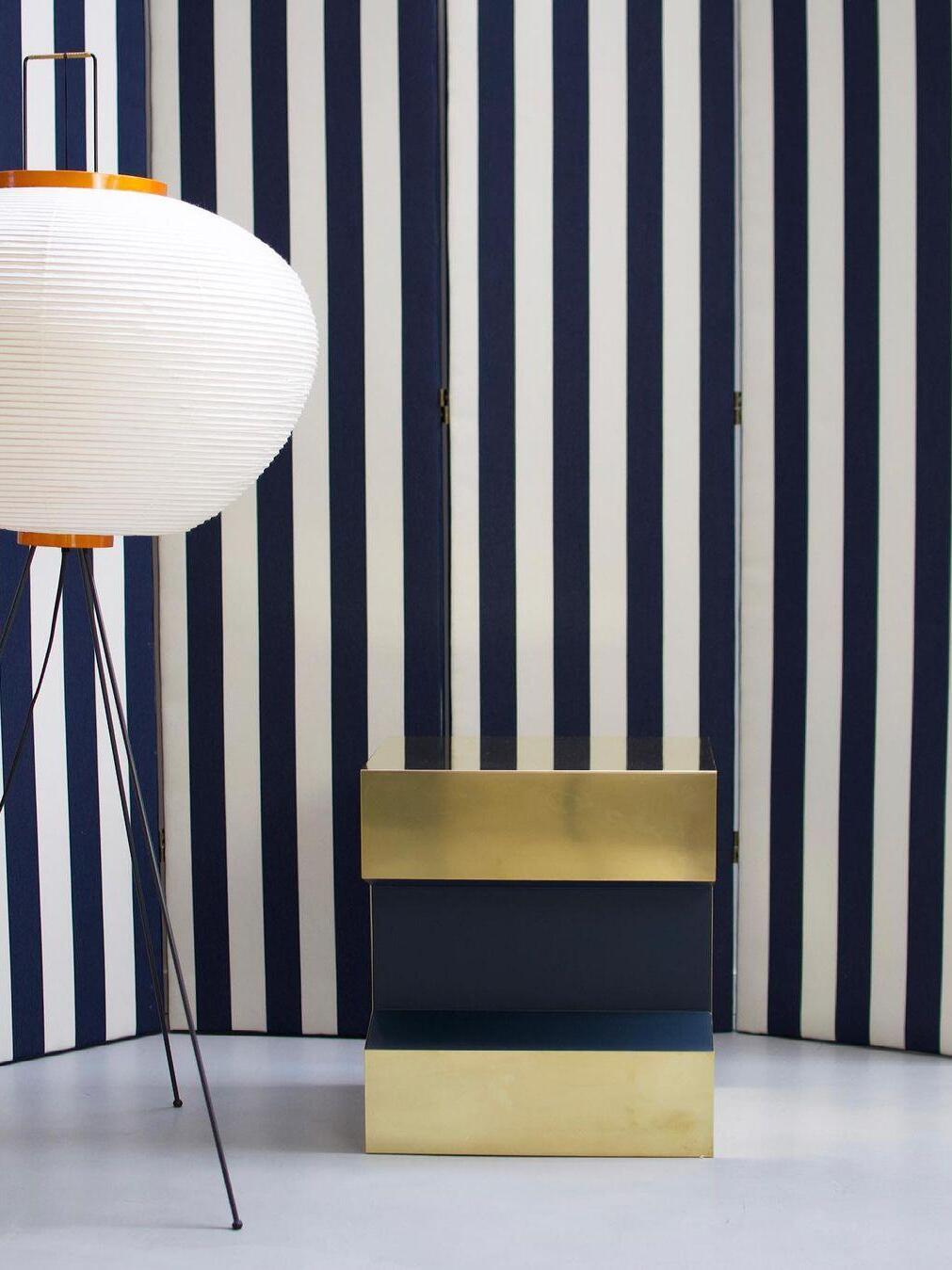 Rounded floor lamp beside striped wall