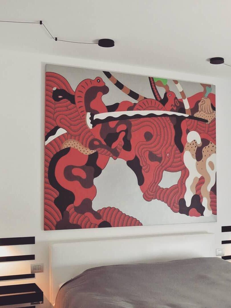Ceiling cable routing above a bed and large red-and-black artwork