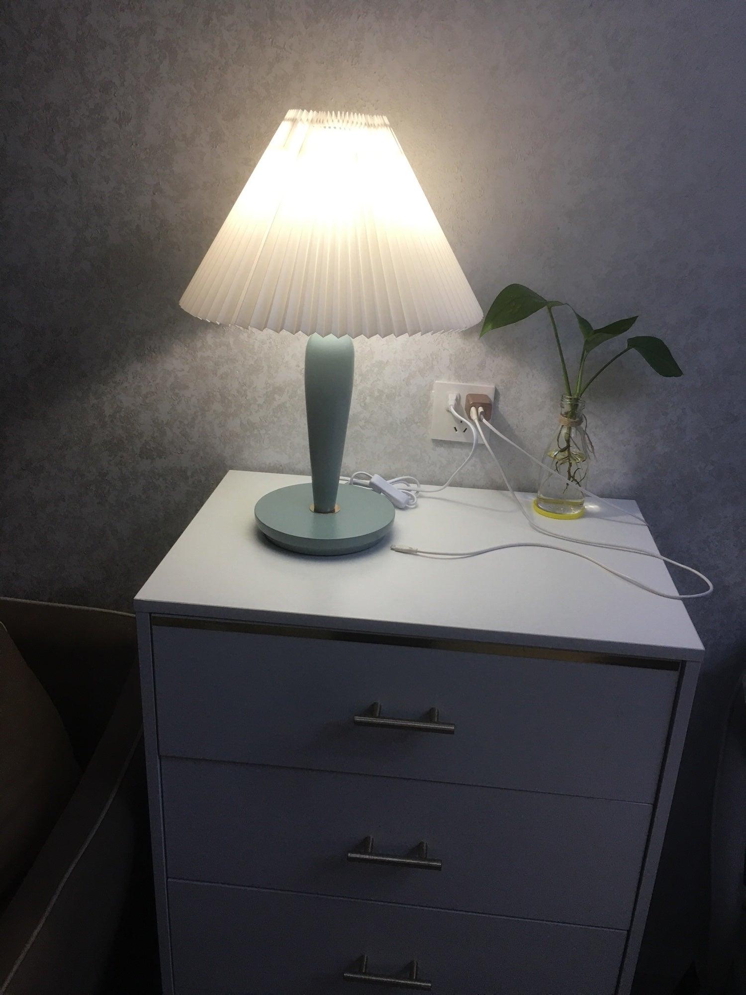 Glowing light-blue lamp on dark bedroom chest