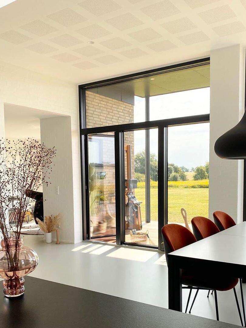 Dark pendant beside a wide garden-facing window