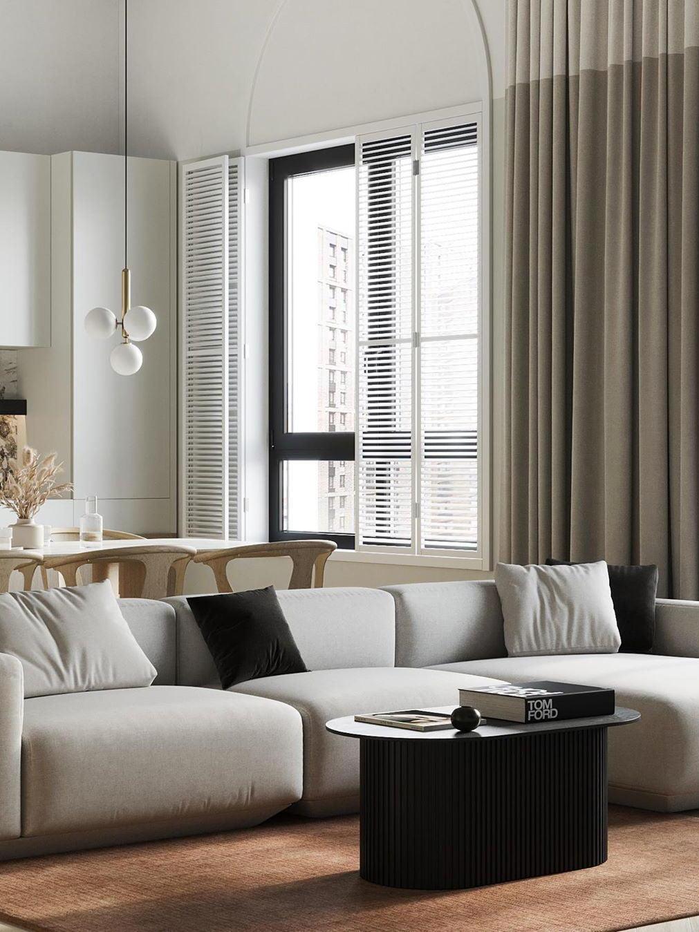 Three white glass globes on a brass-colour stem over a dining area beside a pale sectional sofa