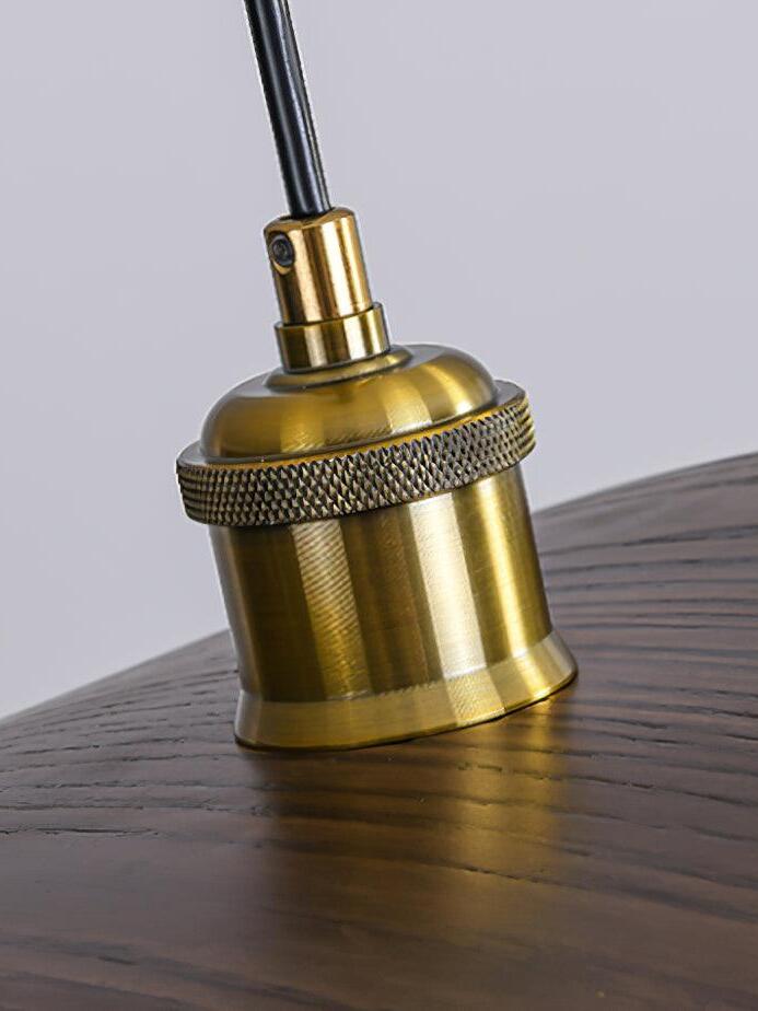 Gold-tone central fitting with a textured ring and black cable above the wood-grain shade