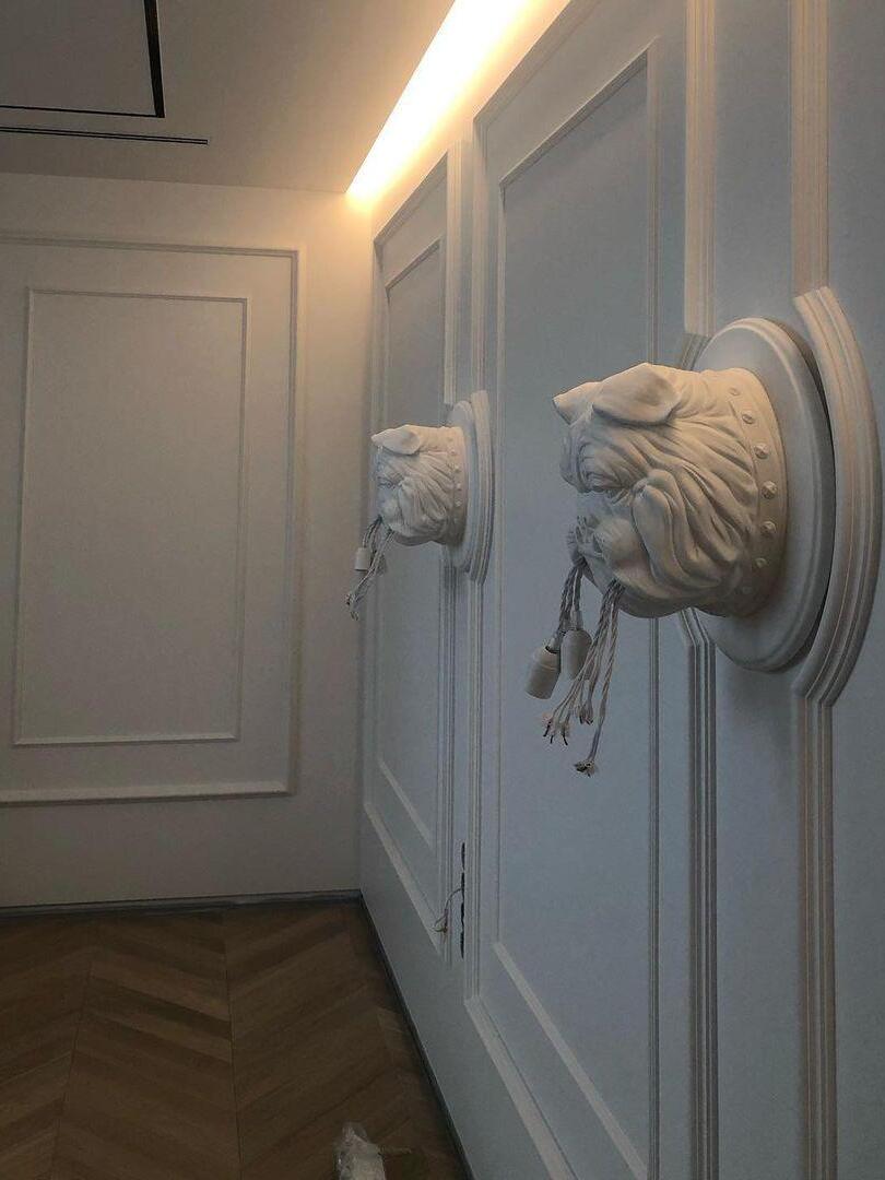 Two white bulldog sconces along a panelled wall