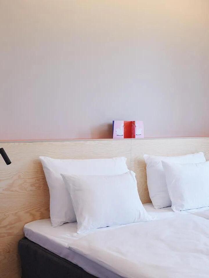 Bedside view with white pillows and a small reading light at the left edge