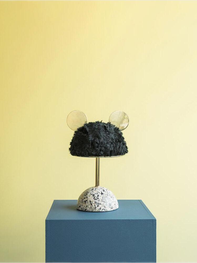 Dark plush table lamp on blue cube against yellow background