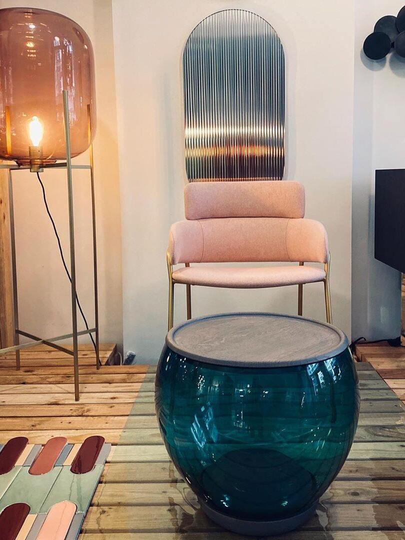 Amber glass lamp beside a pink chair and blue glass coffee table.