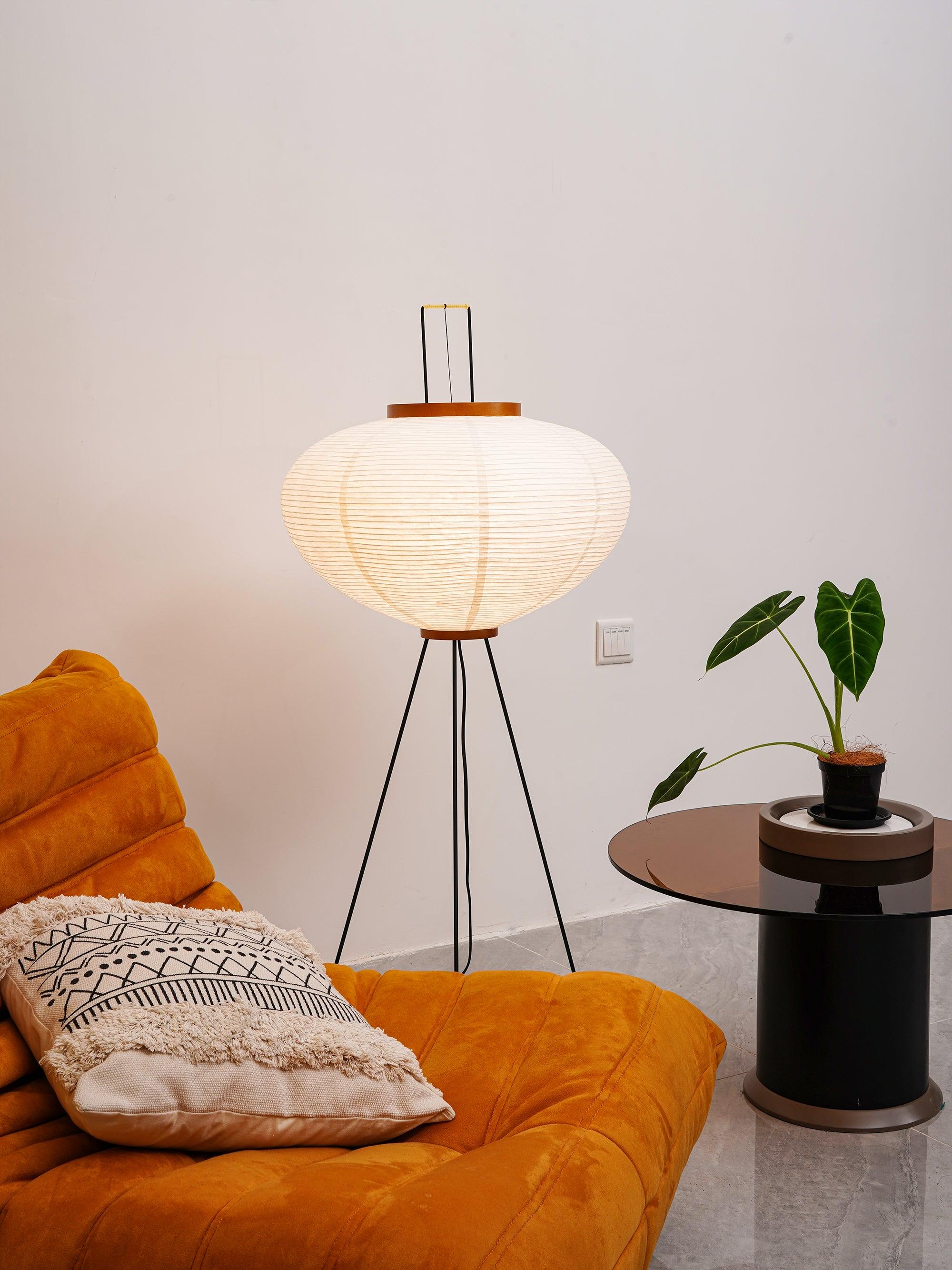 Glowing rounded paper lamp beside orange sofa