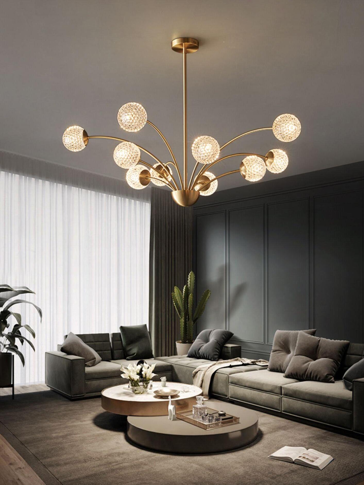 Textured globe chandelier above gray sofas and round coffee tables beside a window and cactus