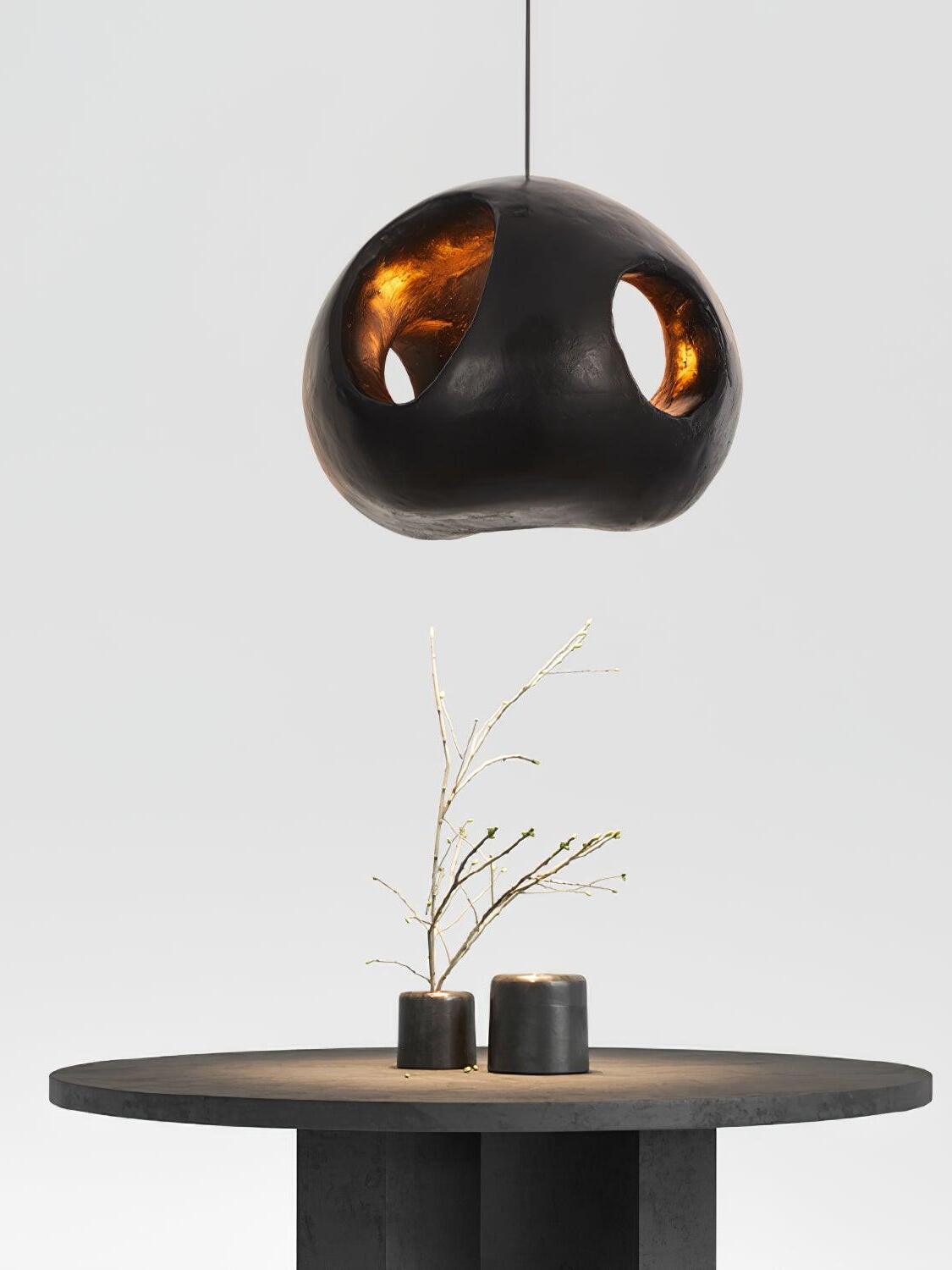 Sculptural black pendant above a dark round table