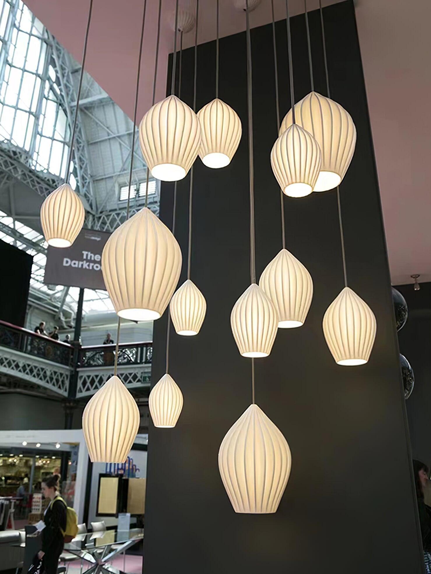 Display of many illuminated ribbed pendant shades in different sizes and hanging positions