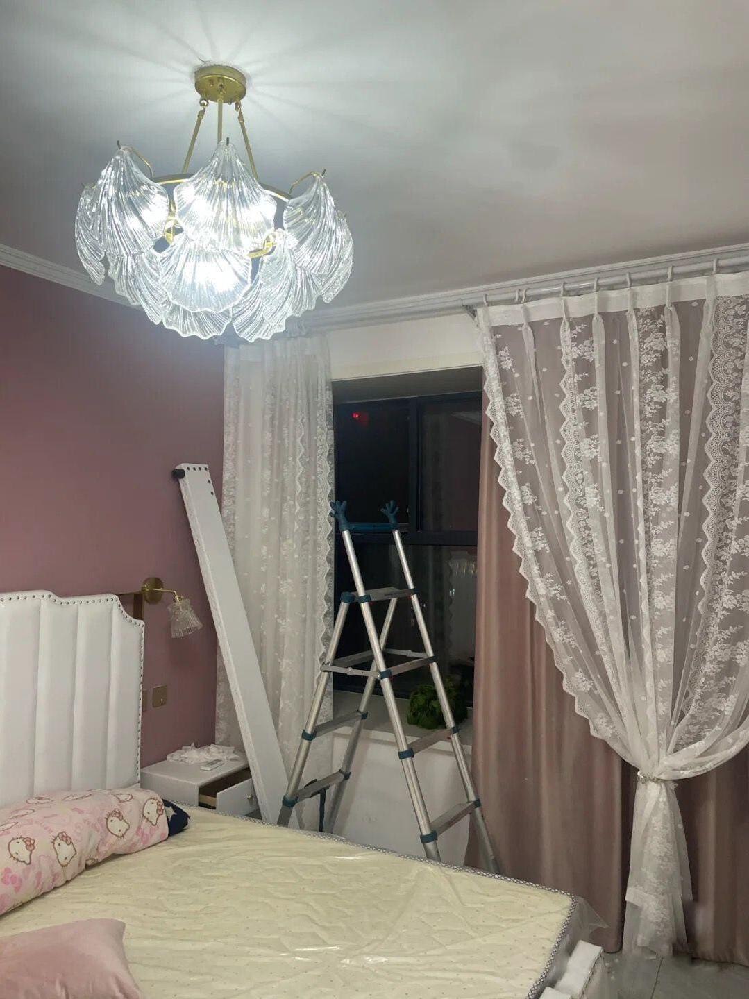 Shell-panel light in a pink bedroom with a ladder and lace curtains