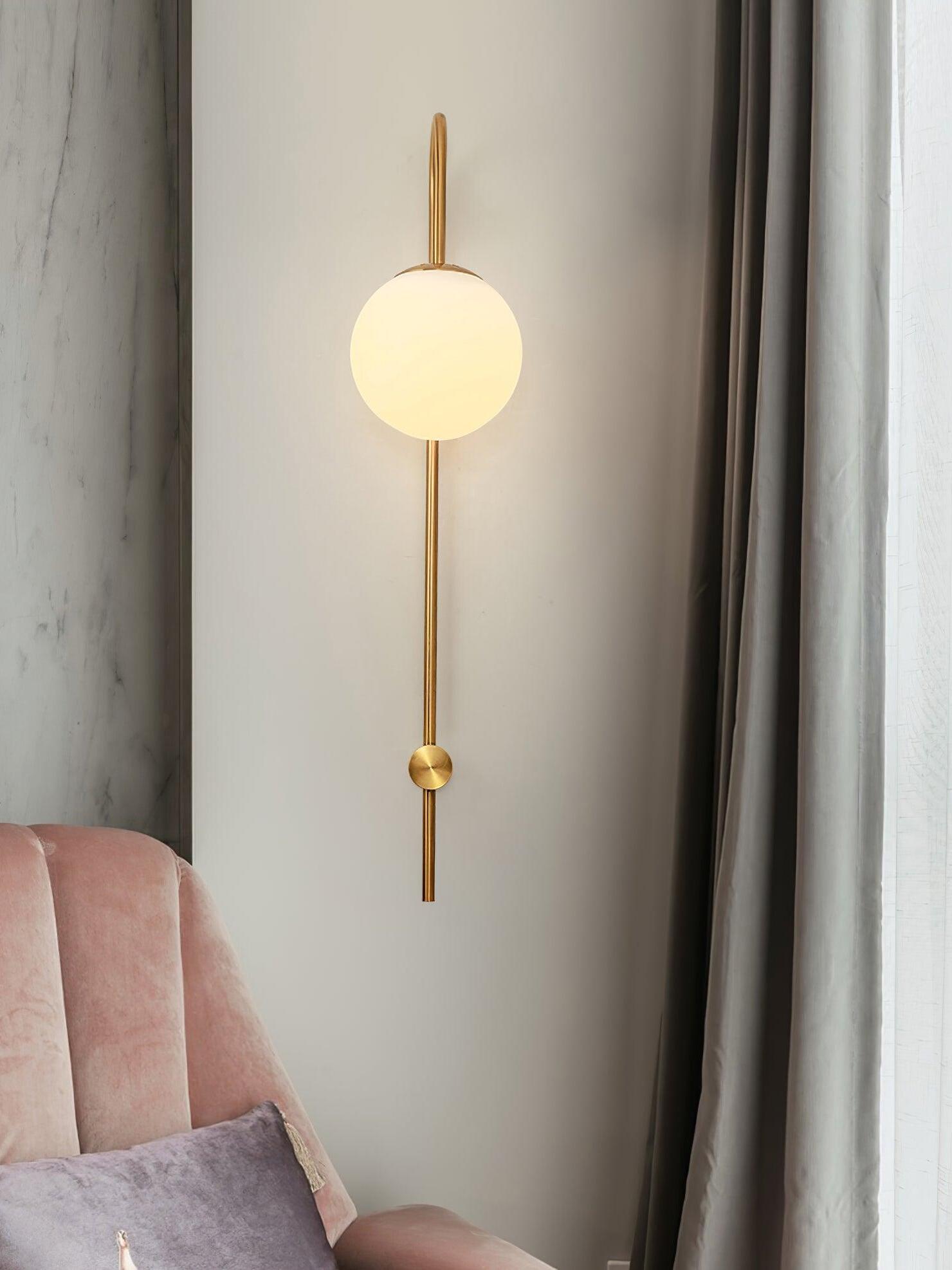Gold curved wall sconce beside curtain and armchair