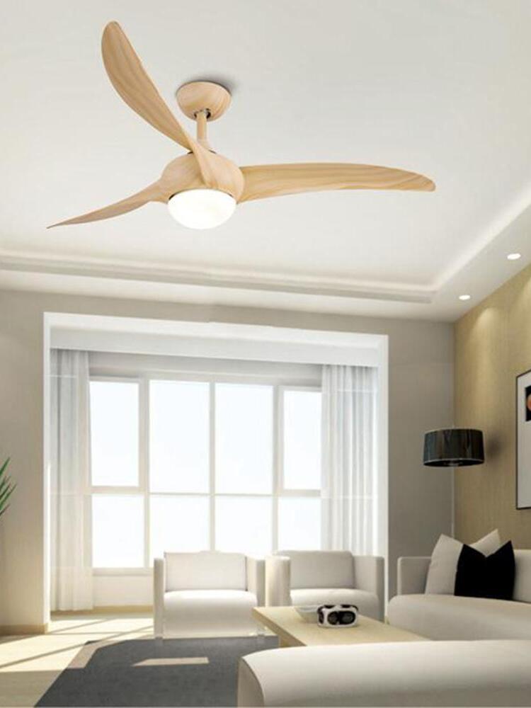 Light woodgrain-looking fan with three curved blades and round light above a neutral living room with white seating