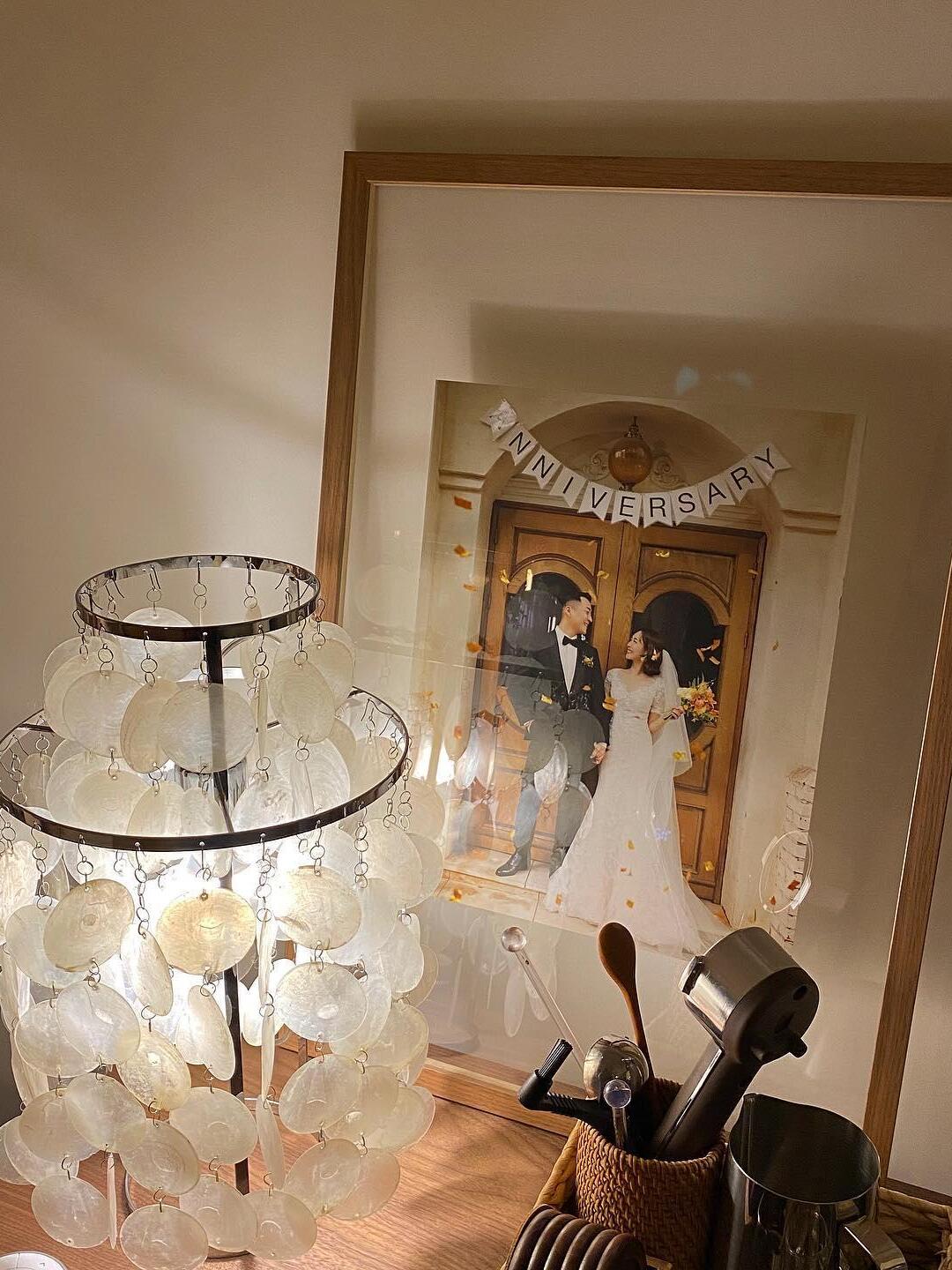 Top of lit shell lamp beside leaning framed artwork