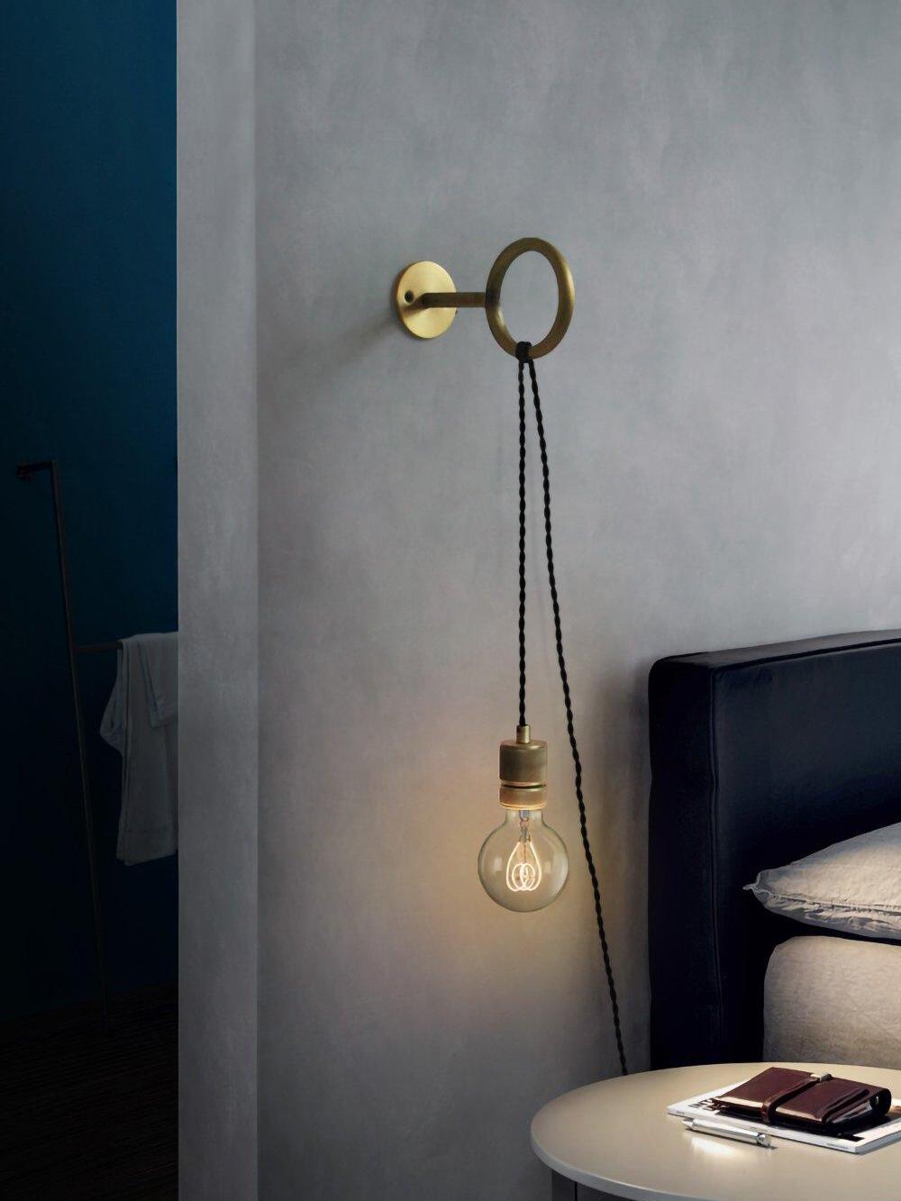 Loop wall light with hanging globe beside bedside table
