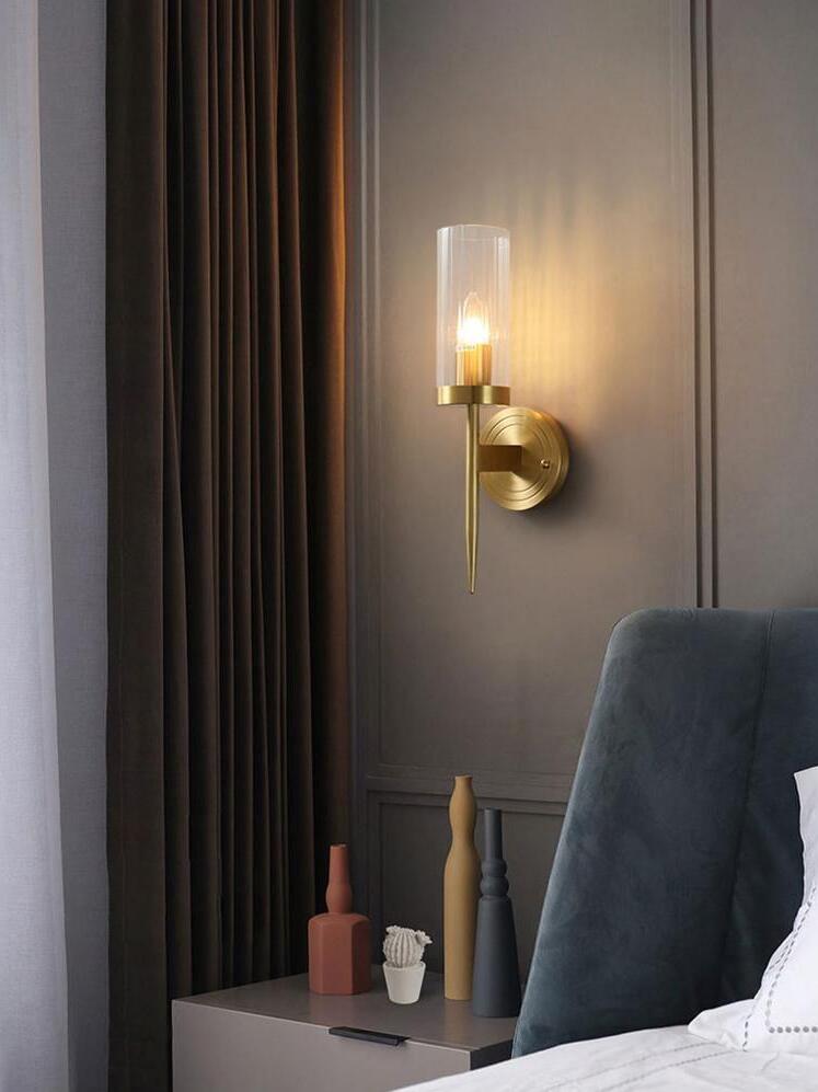 Candle-style wall light beside a dark headboard