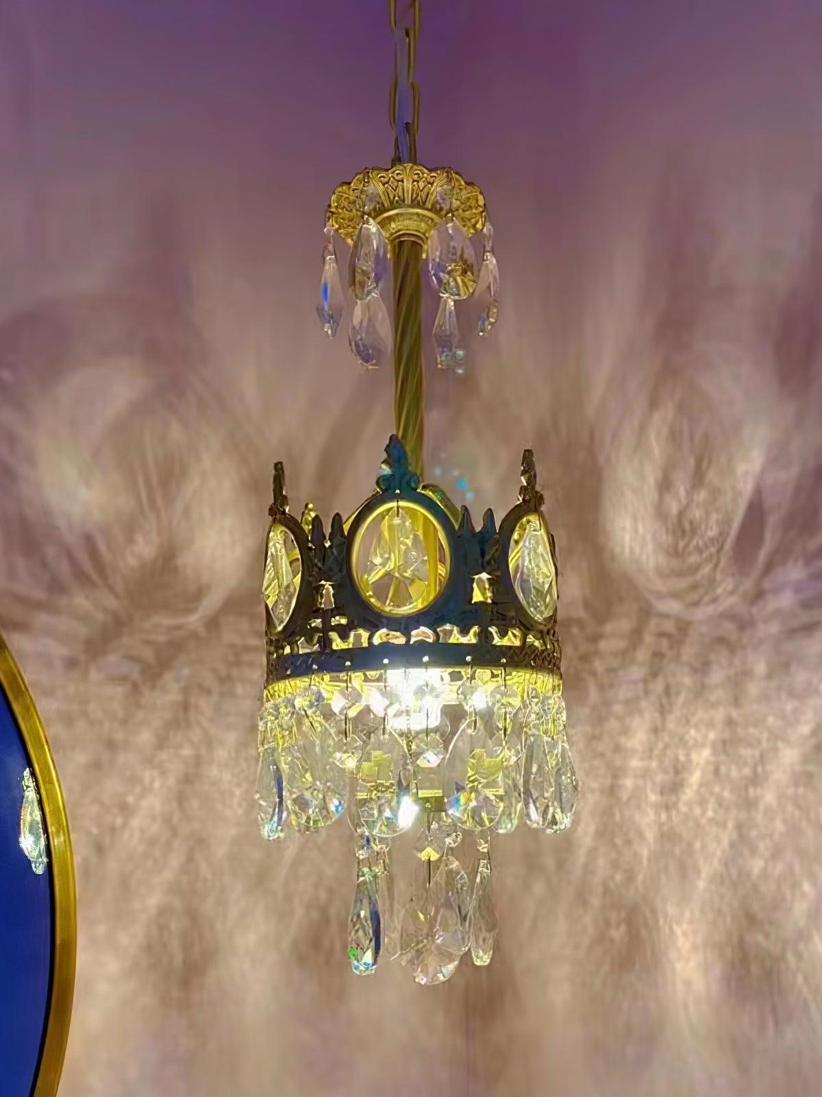 Compact crystal chandelier casting photographed patterns on a pink-purple wall