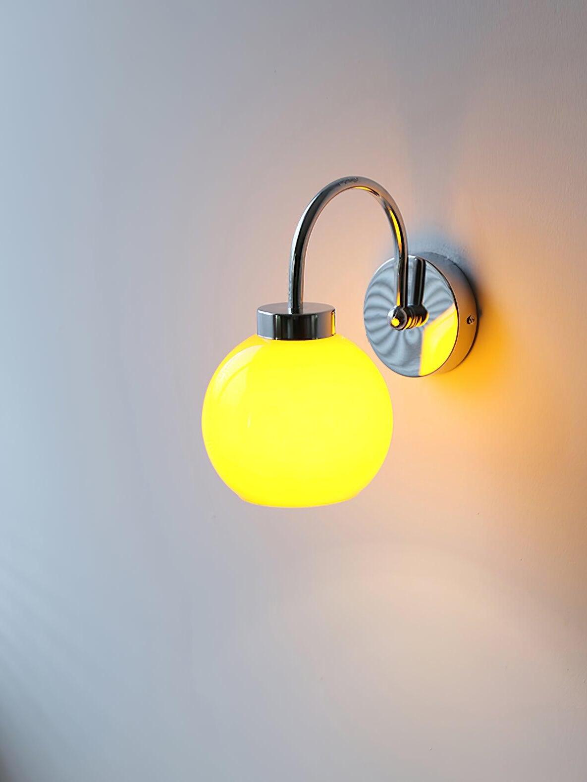Lit yellow-glowing globe below silver-tone curved arm with warm wall halo