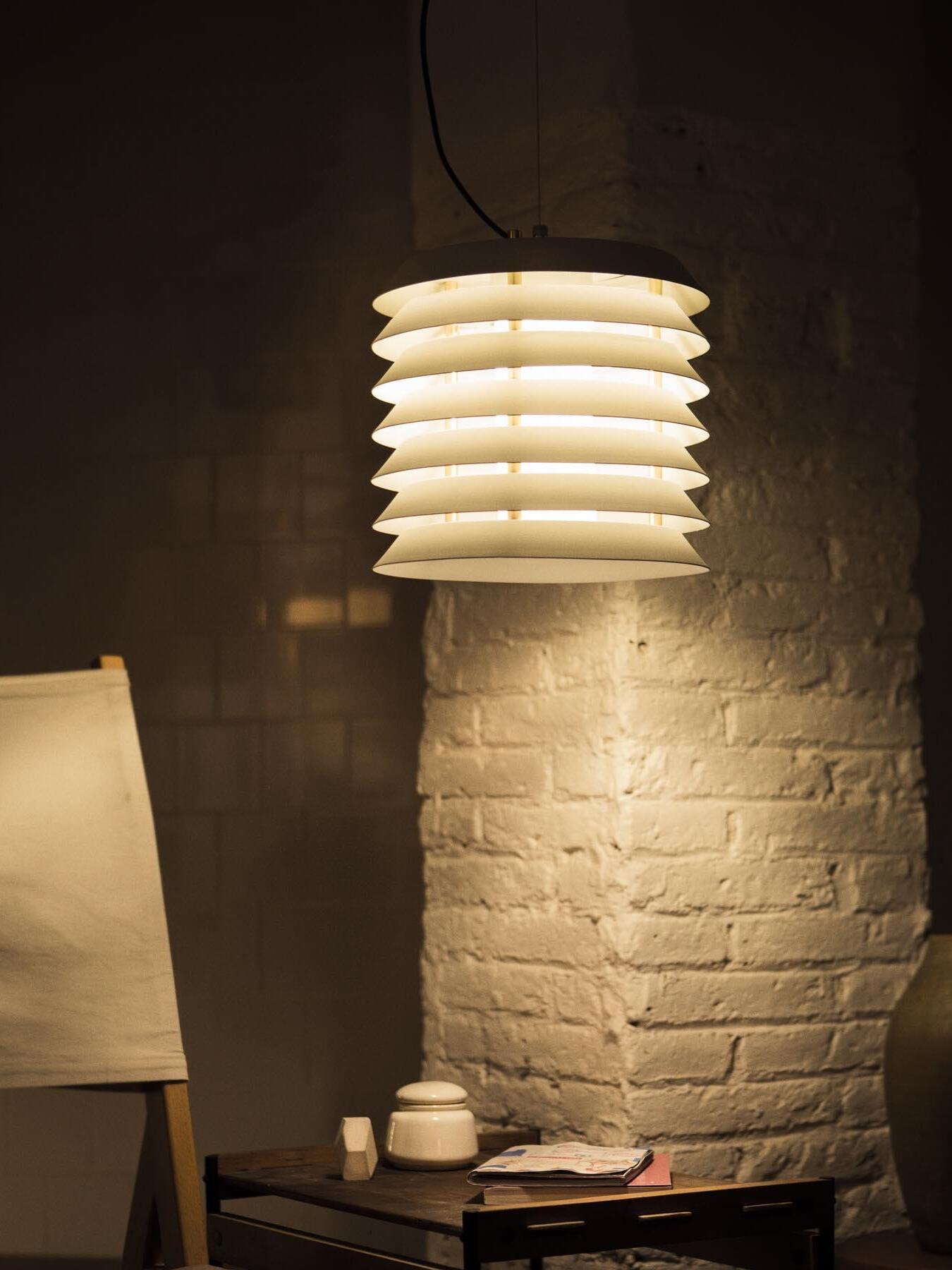 Lit white stacked pendant beside painted brick column and table with cup