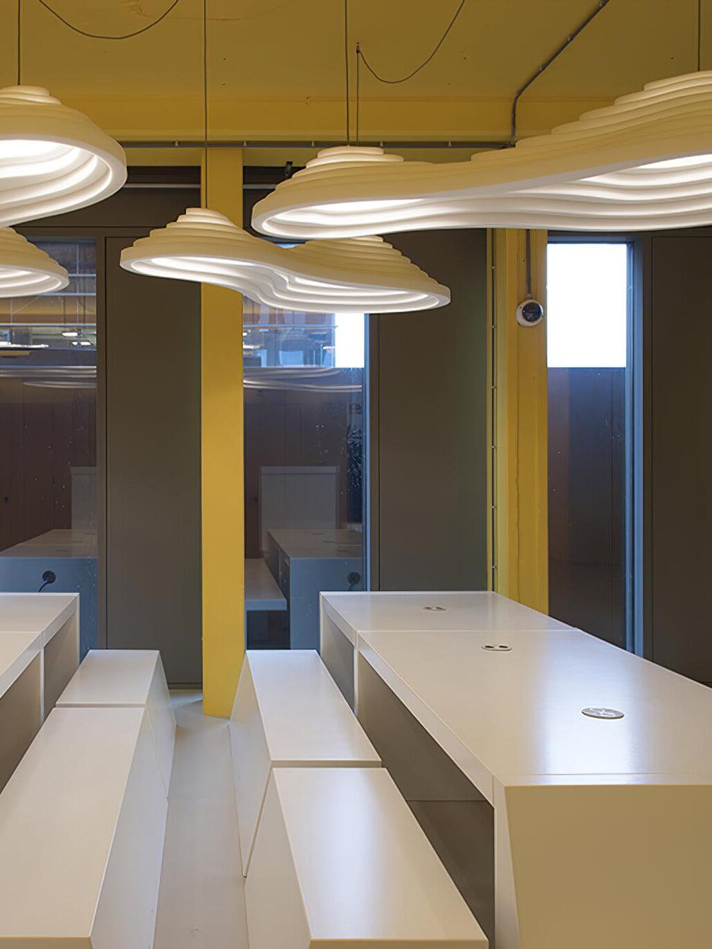 Several white stepped and elongated pendants in a yellow interior above long counters.