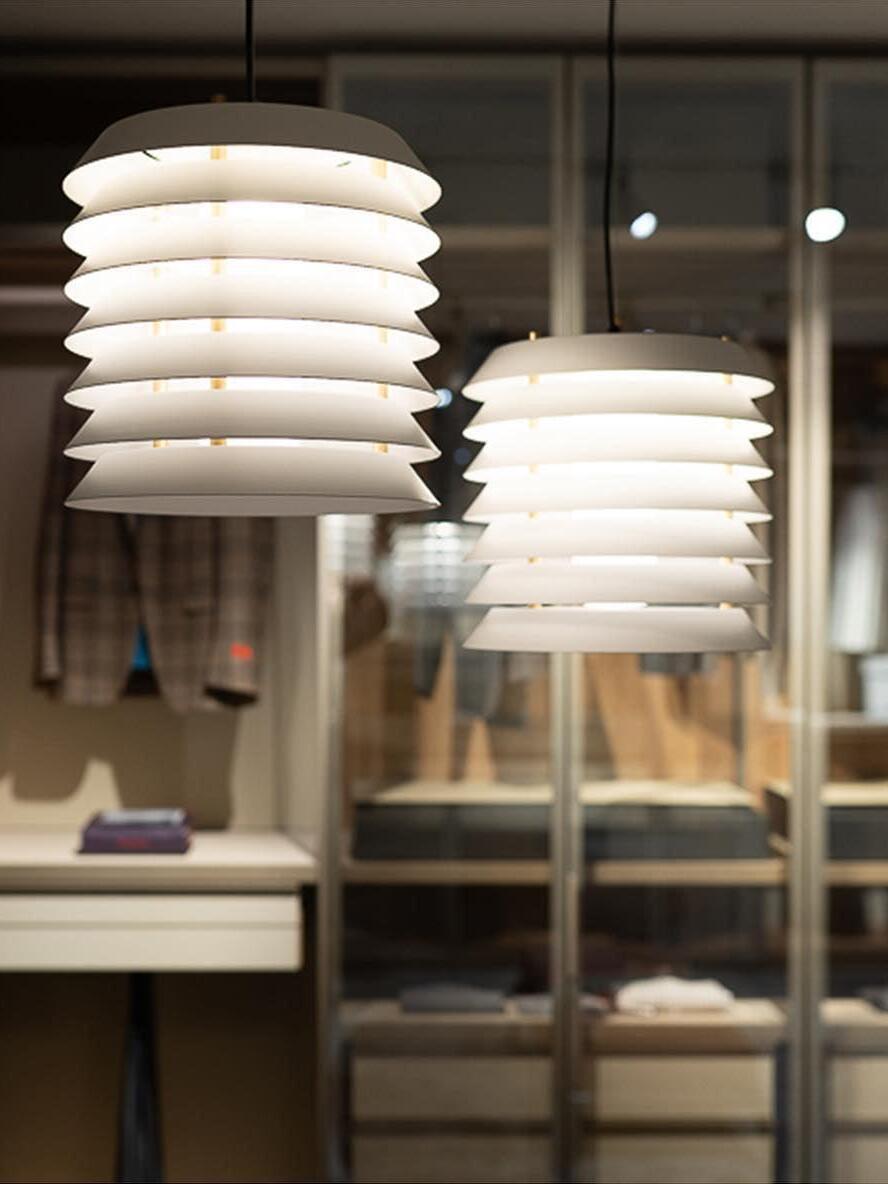Two lit white layered pendants at staggered heights with different apparent diameters