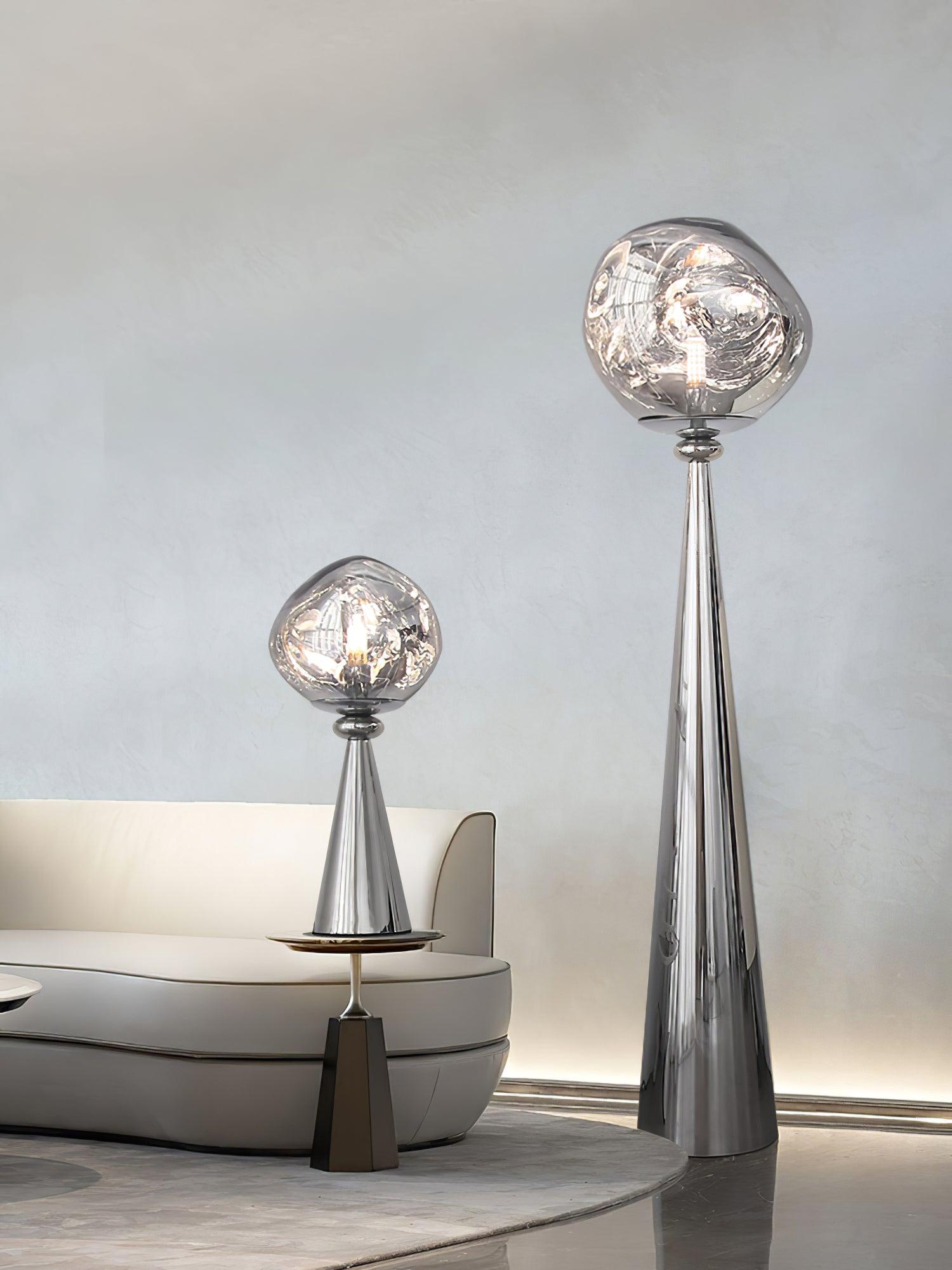 Chrome globe table lamp beside a gray sofa, with a tall floor lamp standing nearby