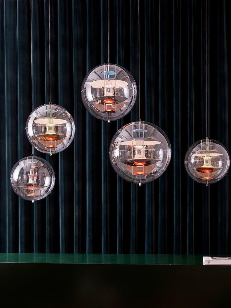 Five separate lit clear globes at staggered heights against dark curtains above a glass counter