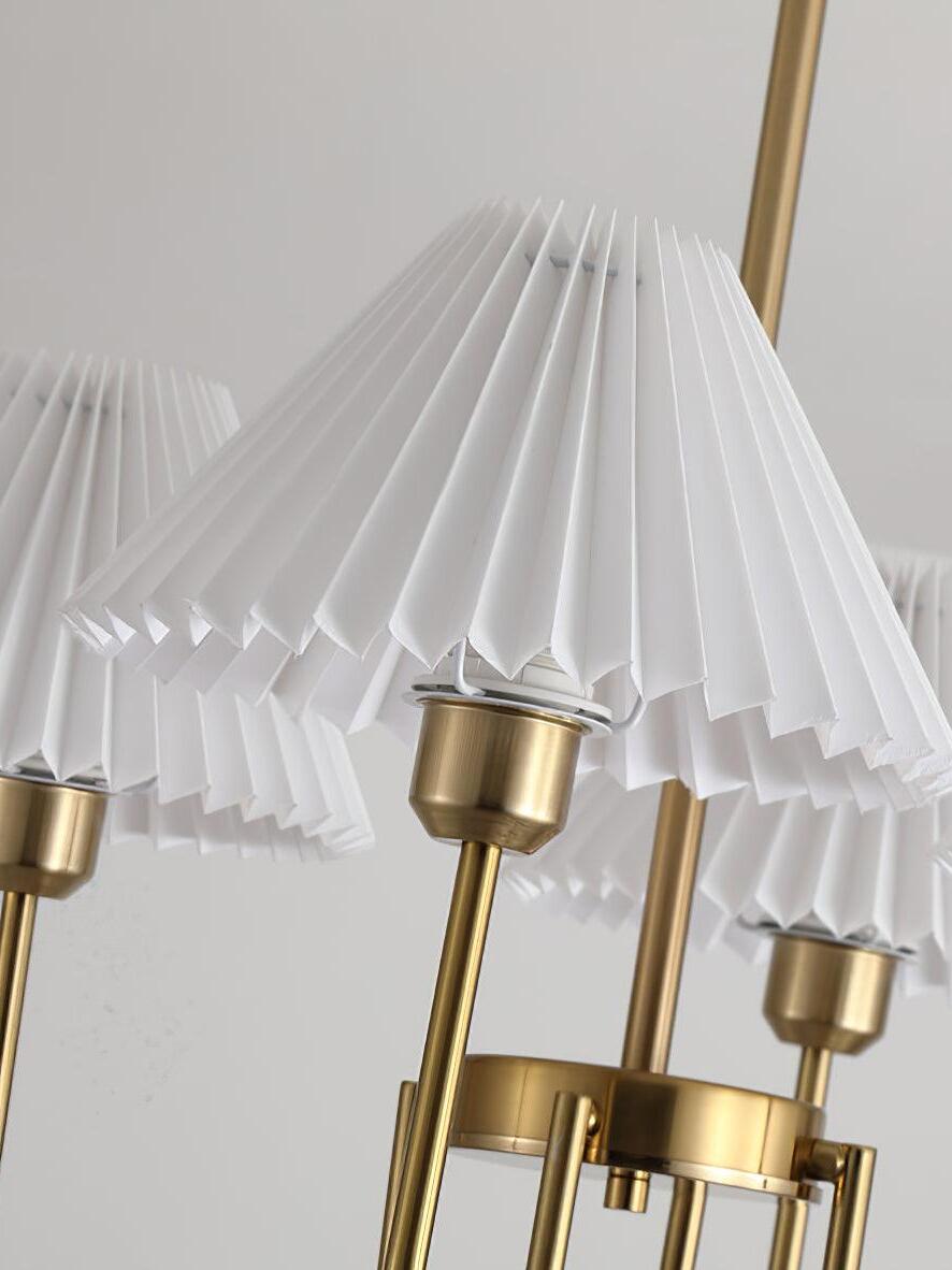 Detail of white pleated shade folds, gold-tone holders and curved chandelier arms