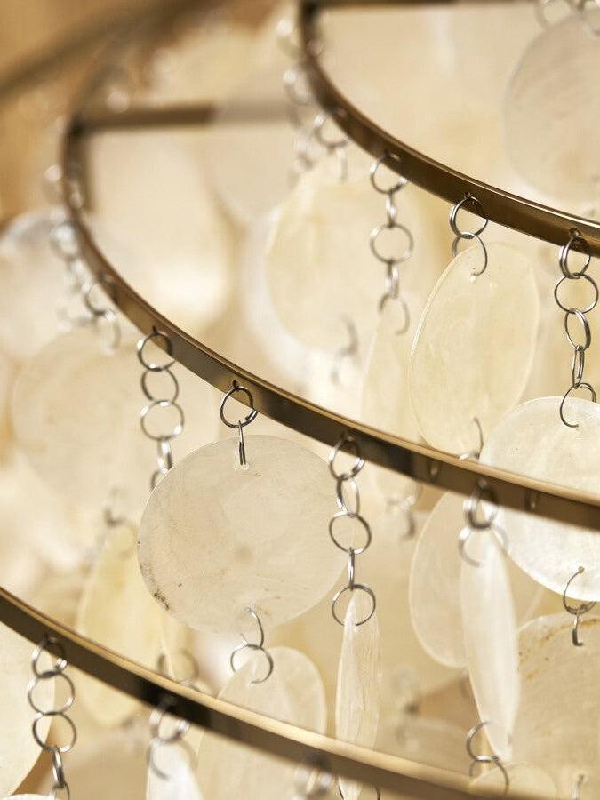 Close-up of pale shell discs linked to a gold-coloured rail