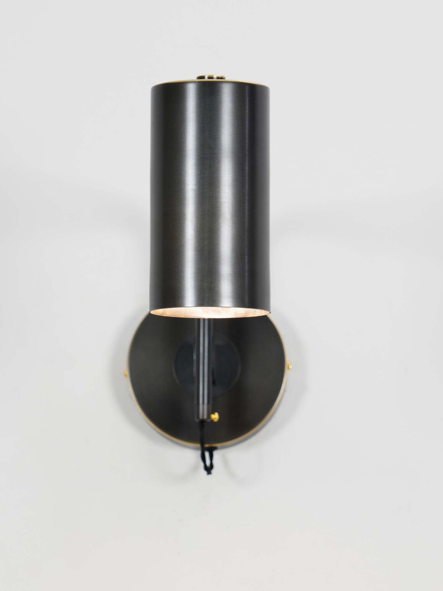 Black cylinder folded close to round wall plate