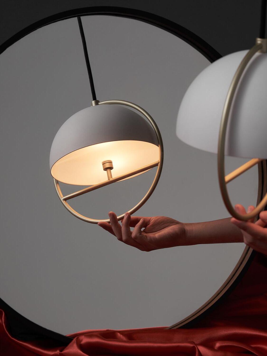 White ring pendant reflected near a round mirror