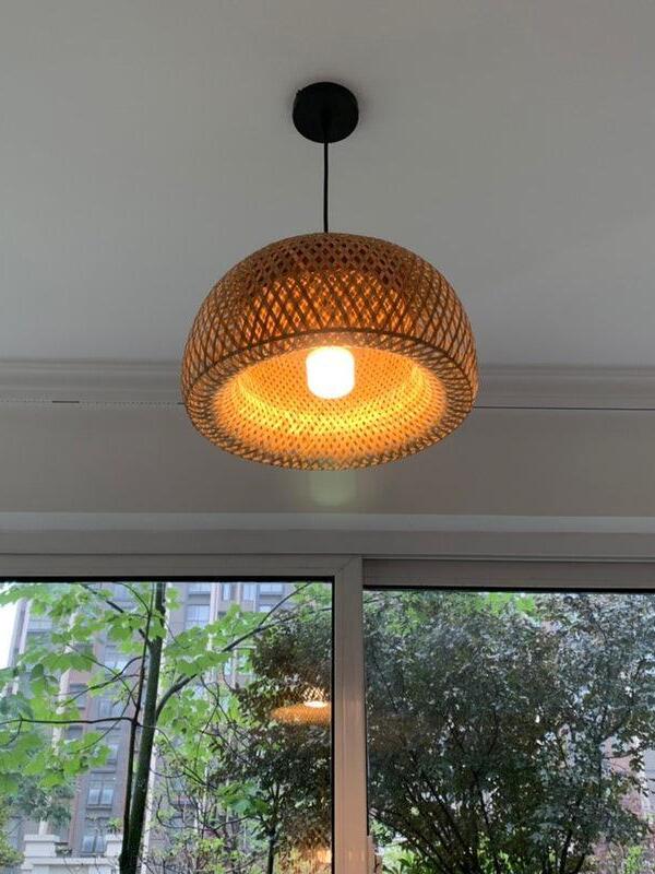 Lit woven bamboo shade suspended near a window