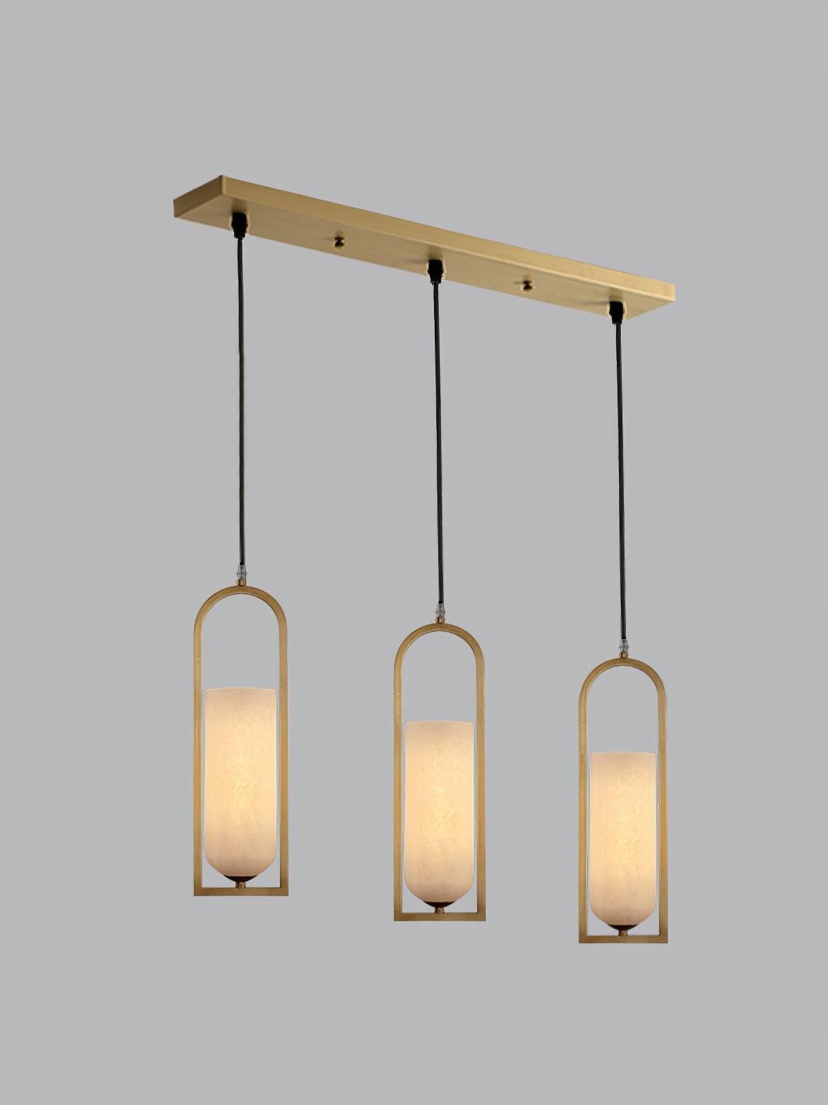 Three glowing Melange pendants in a row below a long rectangular brass-coloured canopy