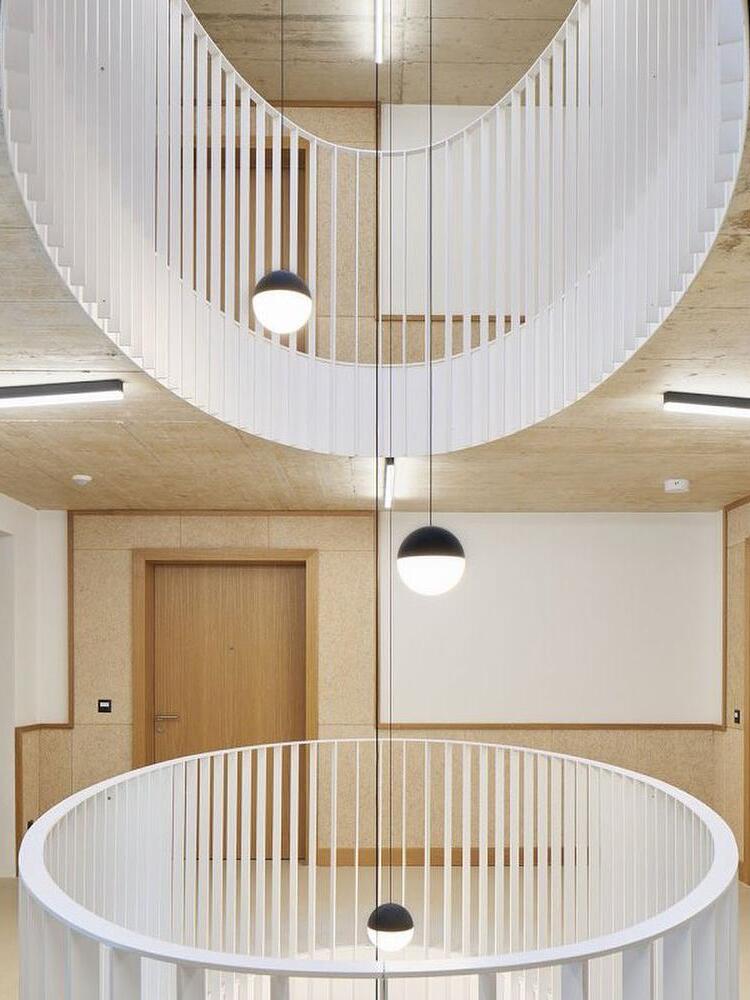 Three black-topped white globe pendants at different drops in a circular stairwell with white balustrades