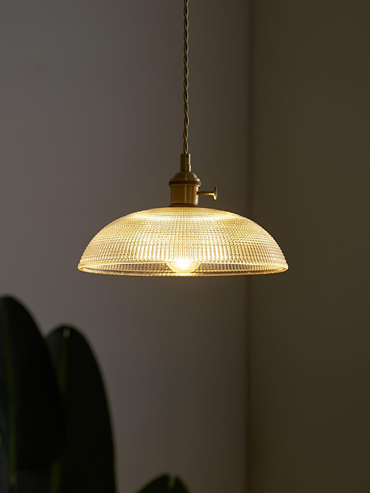 Glass dome pendant glowing against dark wall