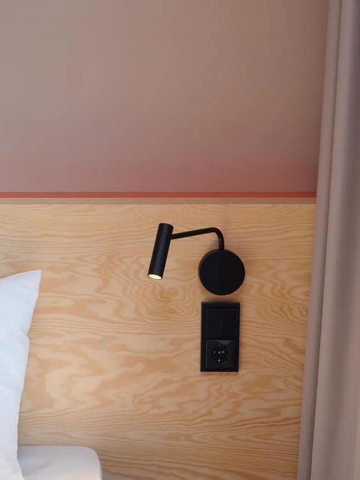 Black reading sconce mounted on a wooden headboard