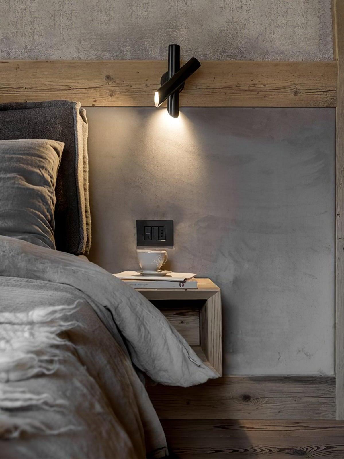 Black crossed-tube wall light above bed headboard