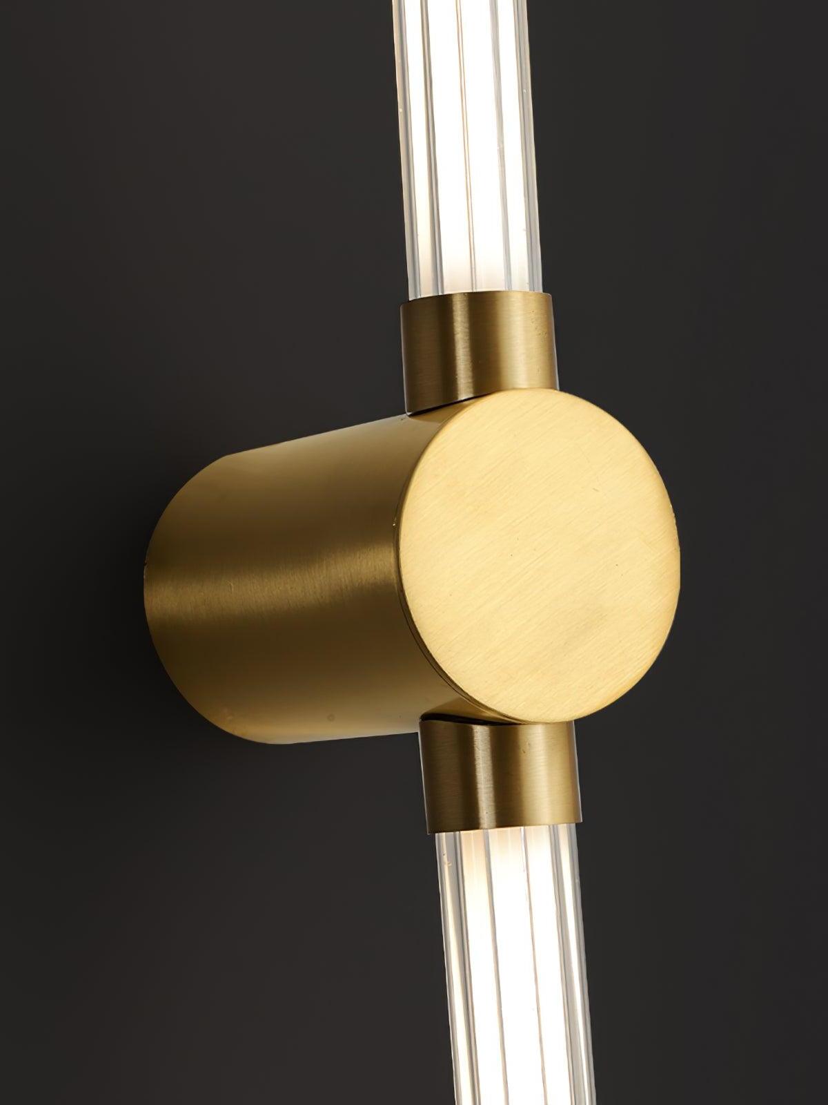 Close view of a brushed brass-tone round wall mount and collars joining ribbed luminous tubes