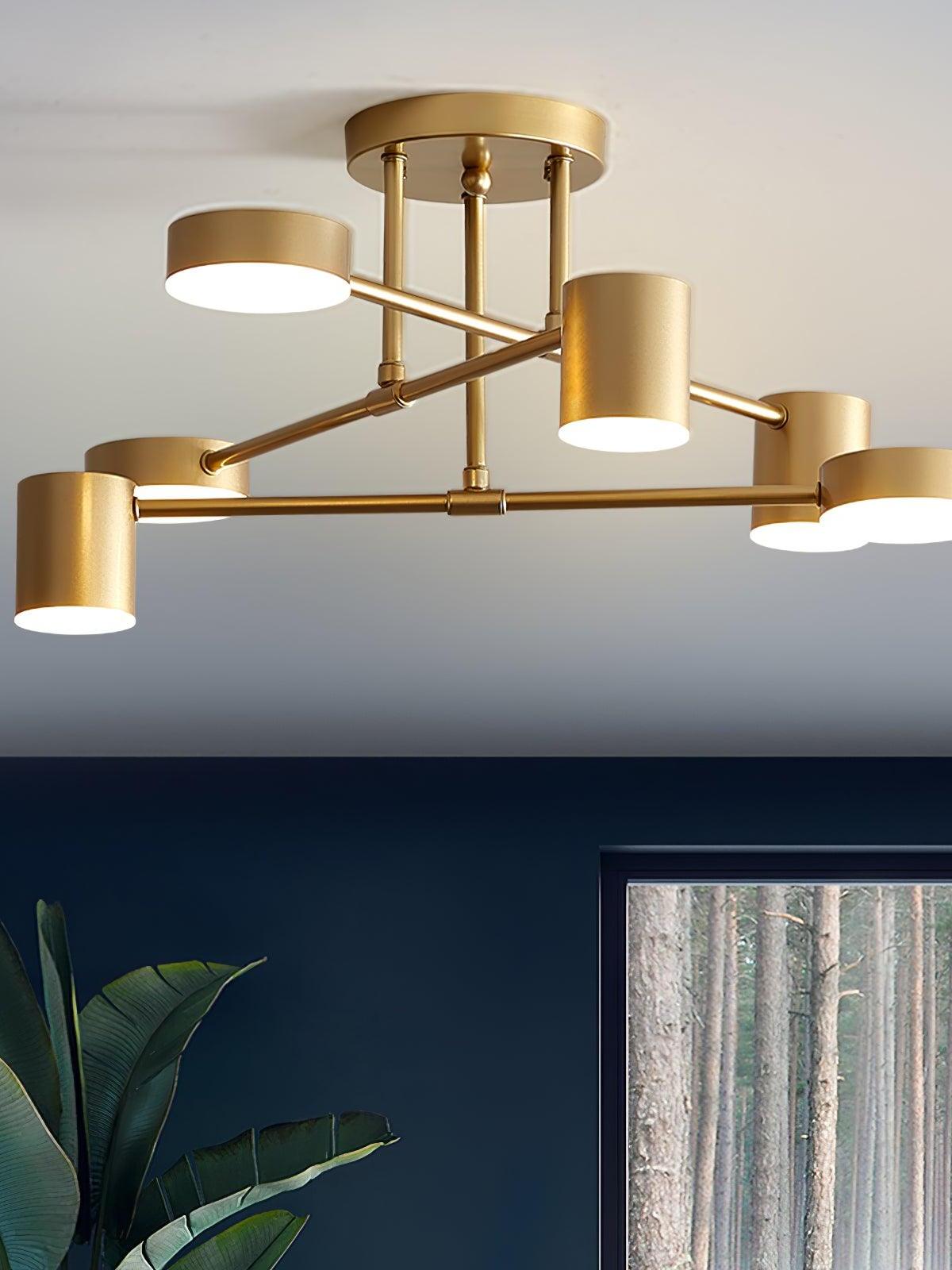 Lit gold six-head crossed-arm ceiling light above a dark blue wall with green leaves and framed forest artwork