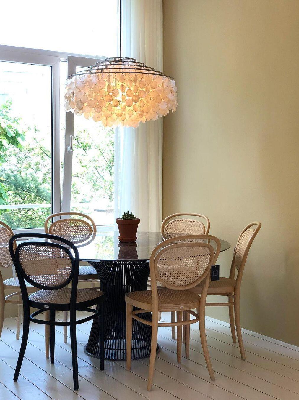 Shell chandelier above a round table and bentwood chairs