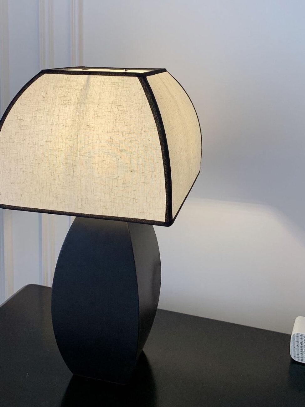 Close view of pale fabric shade and black lamp base