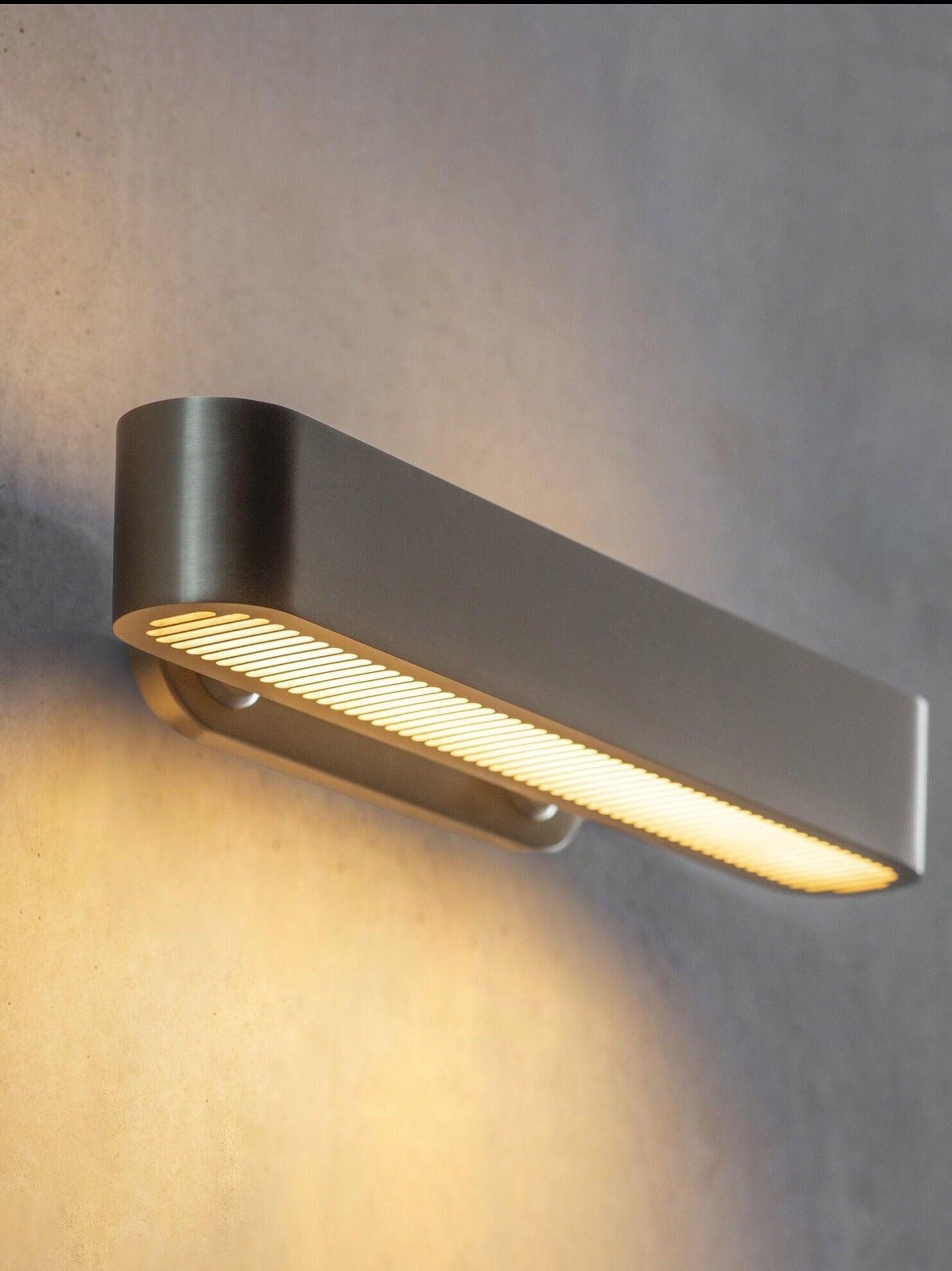 Angled close-up of a horizontal rounded-end wall bar with glowing lower grille slots and short mounting brackets