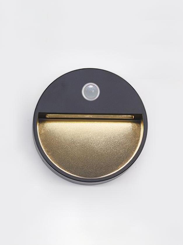 Round black lamp with small dot above light aperture