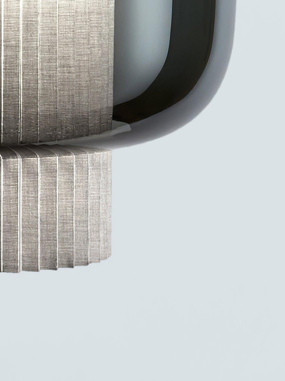 Close-up of grey pleated fabric and the curved lower edge of smoke-grey glass on a Manila T pendant