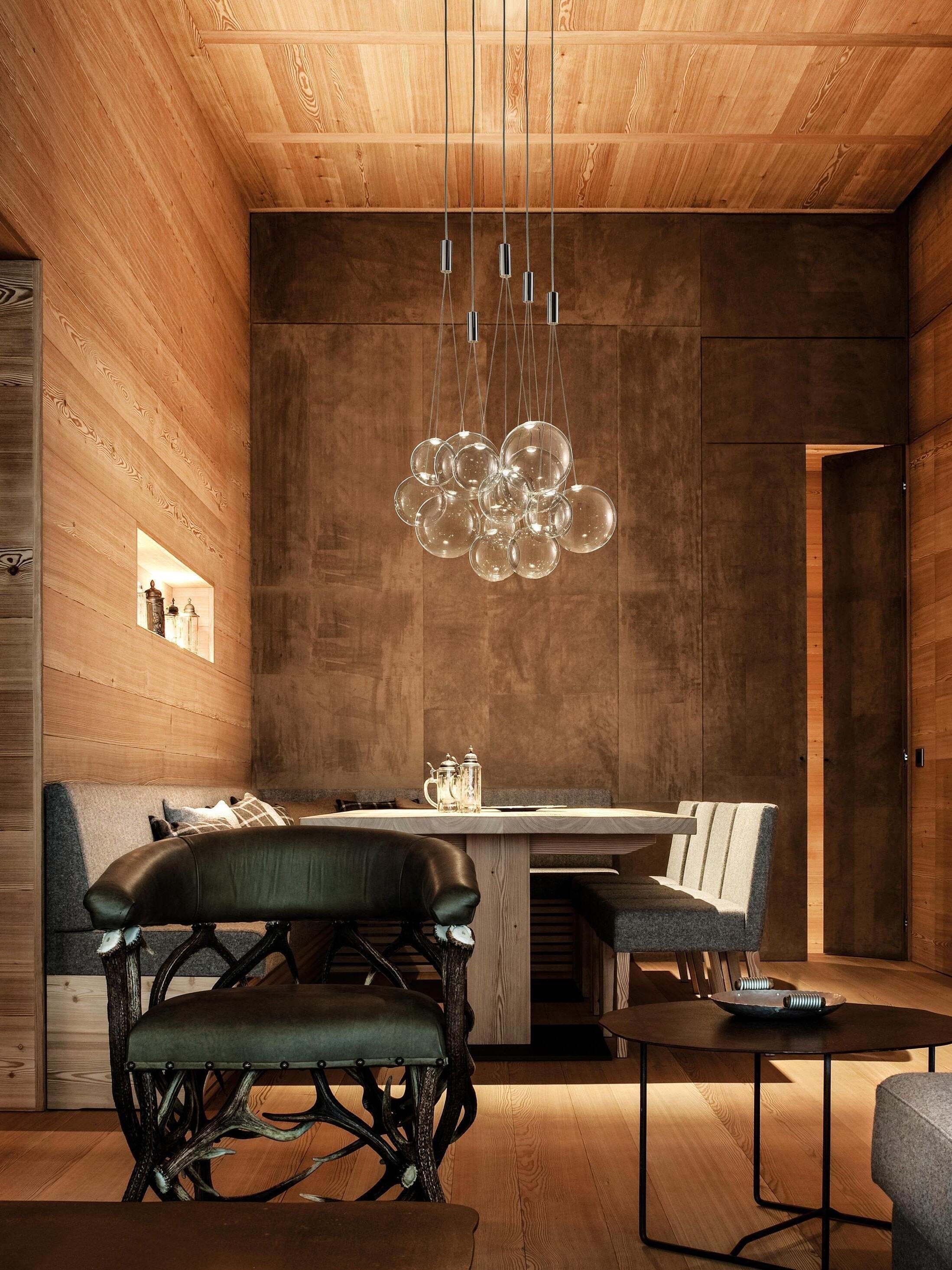Clear bubble clusters above a wooden dining table with teapots and upholstered chairs in a tall wood-panelled room