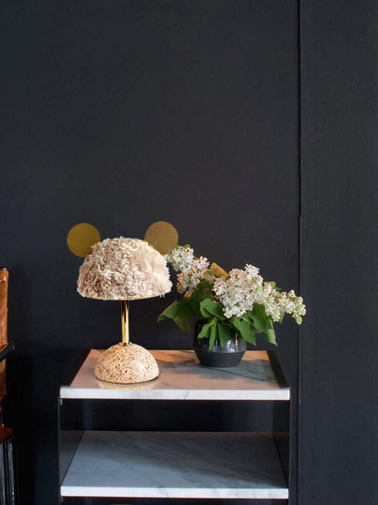 Pale plush lamp beside vase of flowers on low rectangular table
