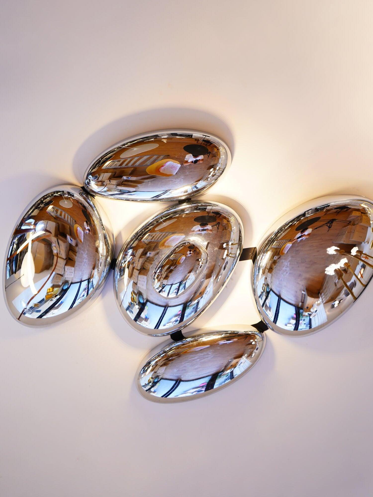 Oblique mirror-finish ceiling cluster with warm room reflections and lower oval