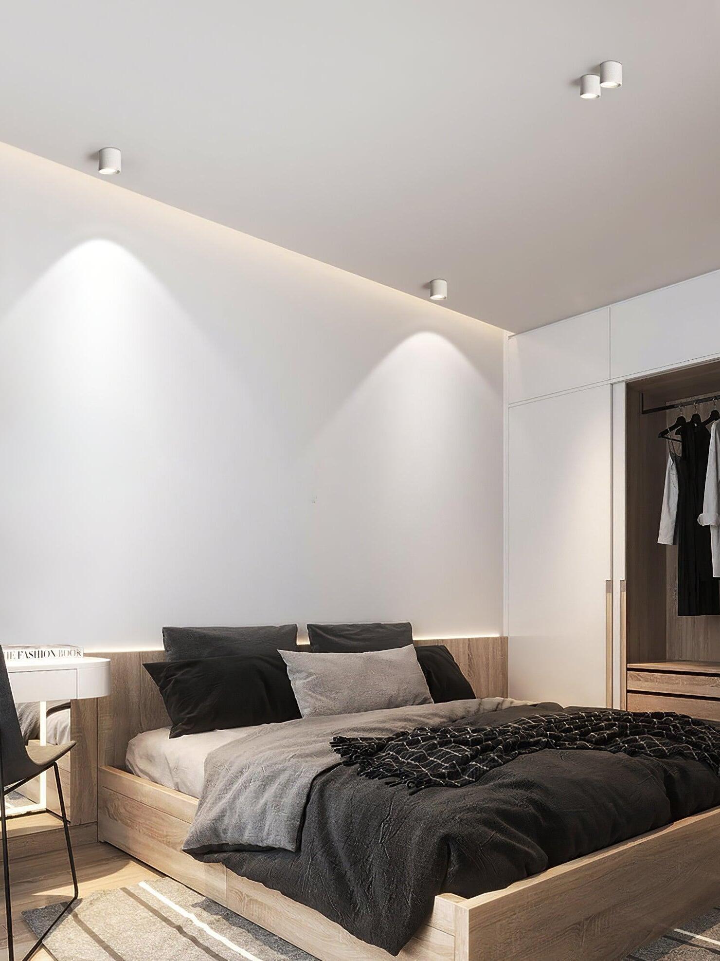 White ceiling lights over a bed and open wardrobe, with two fixtures close together and light pools along the wall