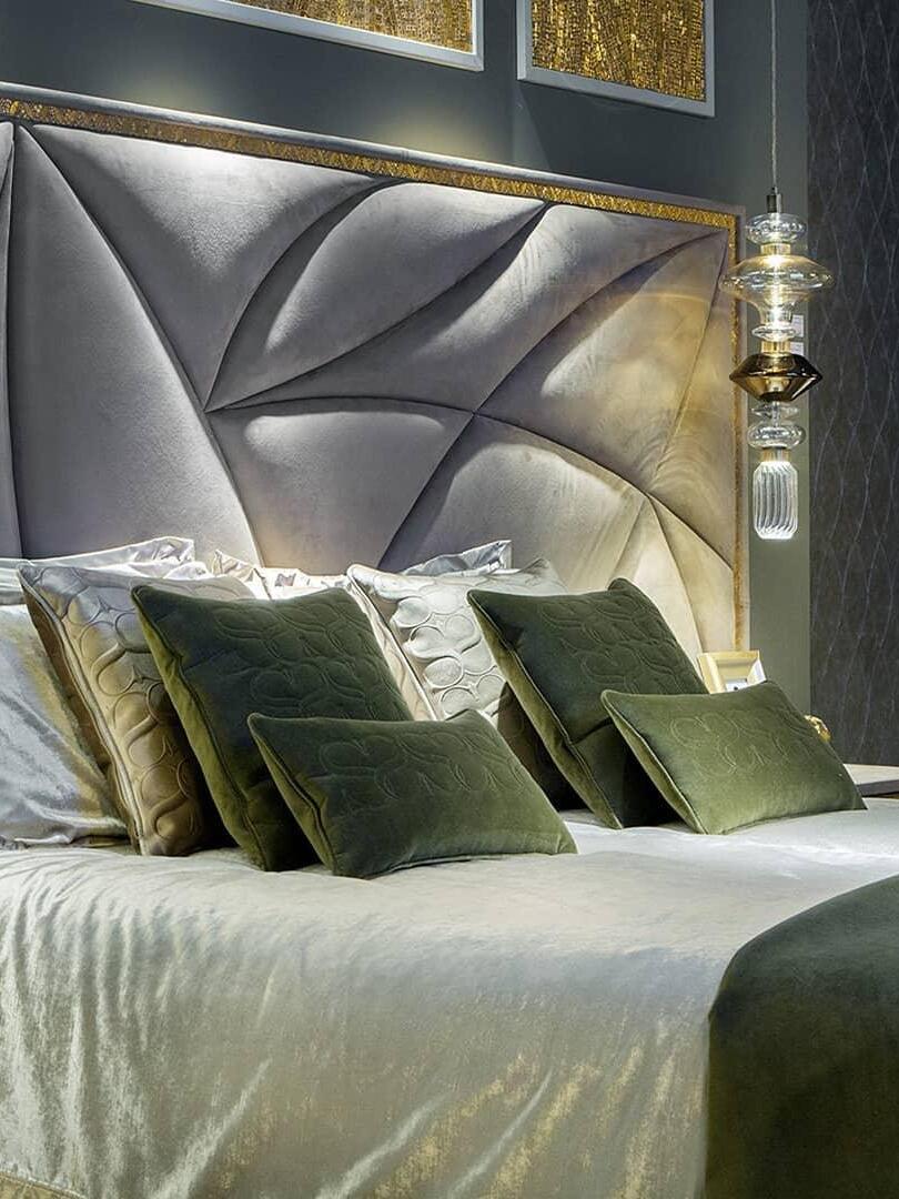 Glass pendant beside a bed with dark green throw